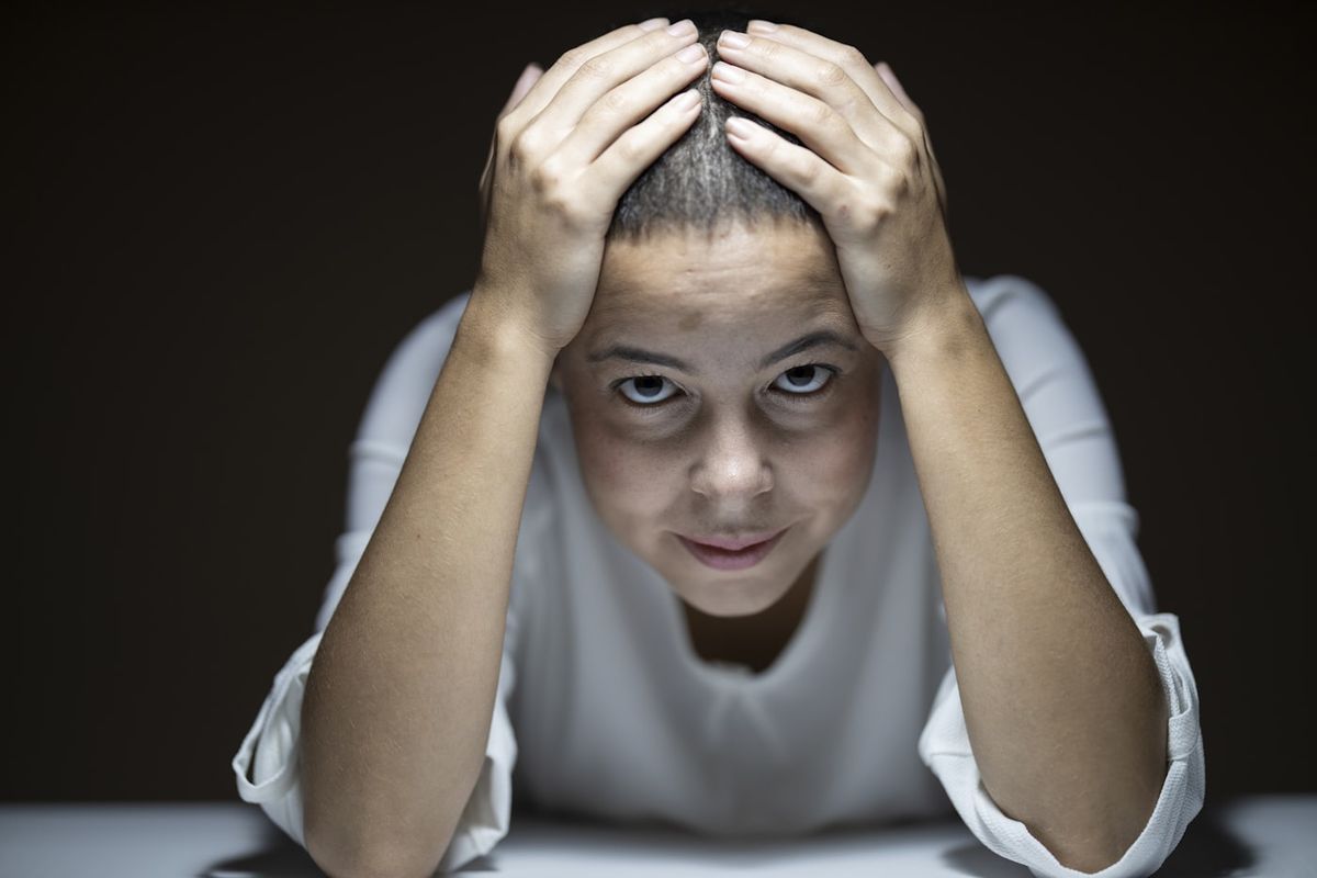 Person holder hendene mot hodet ved hodepine