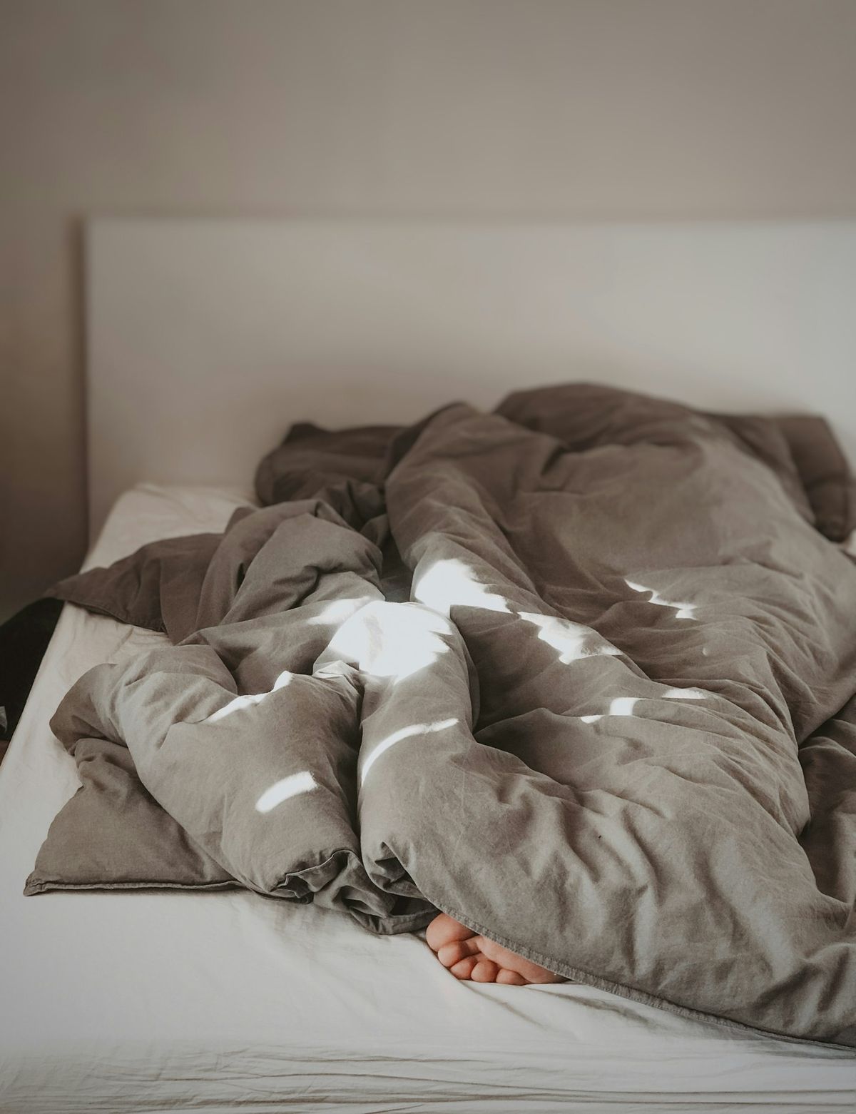 Person i seng under teppe om natten